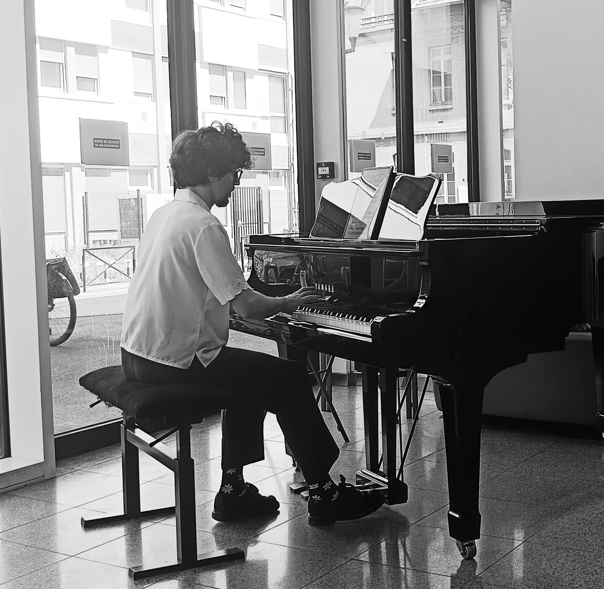 Photo en noir et blanc d'Anthony Mounier, vu de dos au piano, lors d’un concert du Festival des Fièvres musicales 2026, édition spéciale Maladies rares, organisé par l’AP-HP en partenariat avec les facultés de Santé et de Lettres de Sorbonne Université.